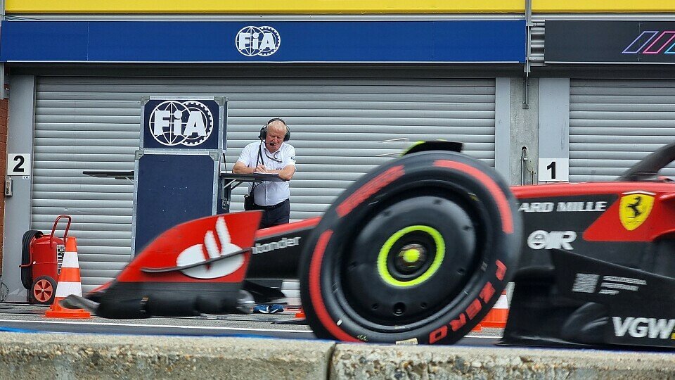 Der Technische Delegierte der FIA, Jo Bauer notiert etwas, während ein Formel-1-Auto von Ferrari in der Boxengasse fährt.