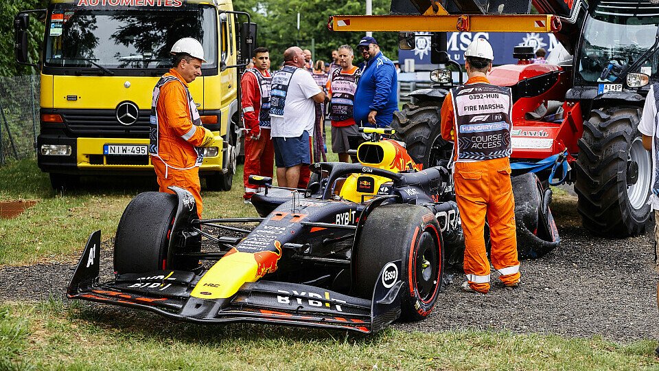 Der zerstörte Red Bull von Sergio Perez, abgestellt auf der Wiese hinter der Absperrung
