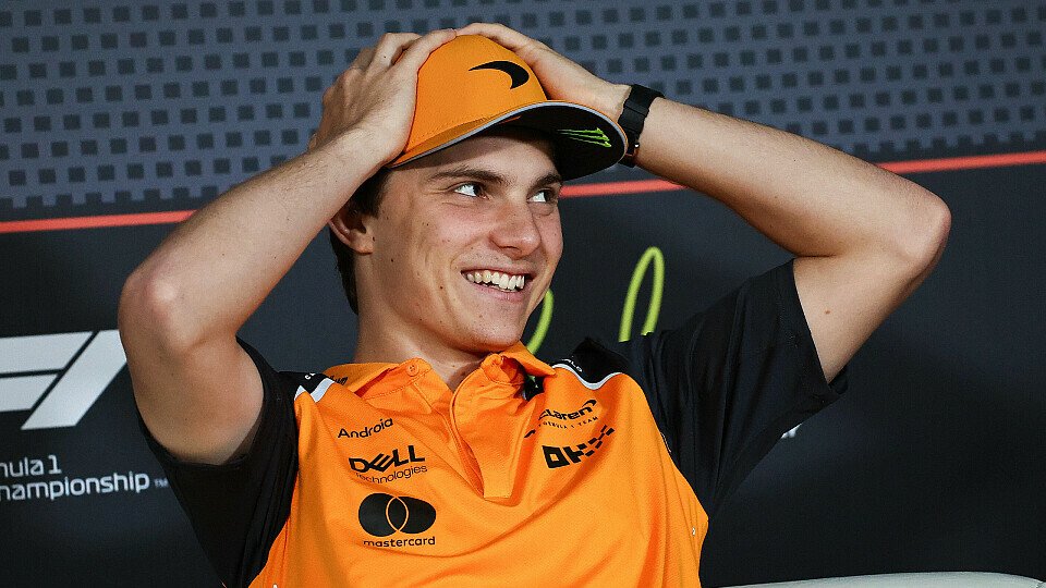 Oscar Piastri greift sich lachend in der Pressekonferenz an die Kappe
